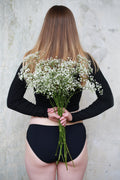 Model Klasické hladké čierne na modelke Majde držiacej v rukách biele kvety.